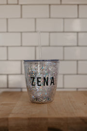 Sparkly cup with a straw that says ZENA on it. There is lots of glitter in the cup and perfect for margaritas