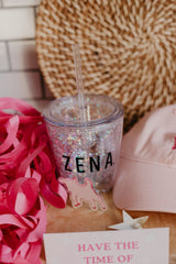 Sparkly cup photographed with a pink goat sticker and a pink goat hat